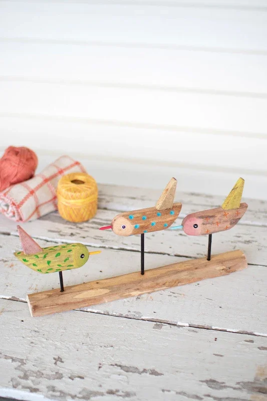 Three painted wooden birds on a base